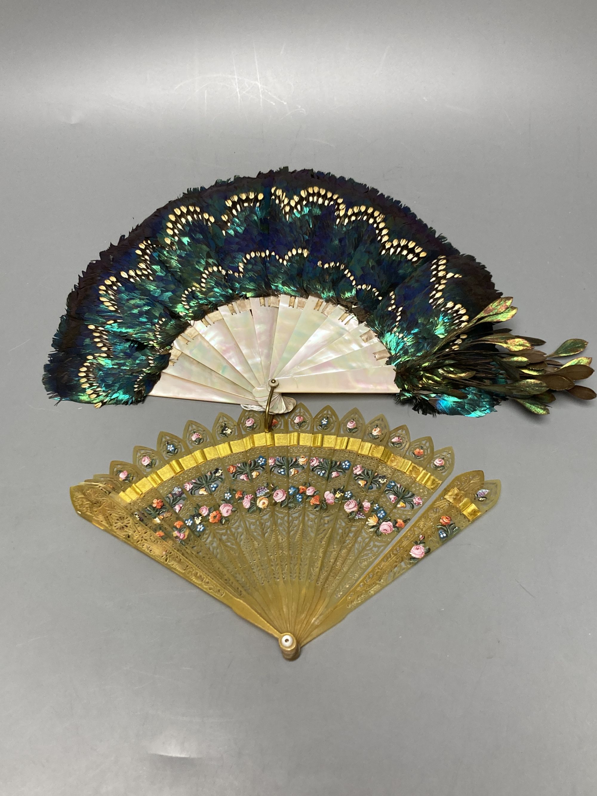 An early 20th century peacock? feather and mother of pearl fan and an early 19th century French painted horn brise fan